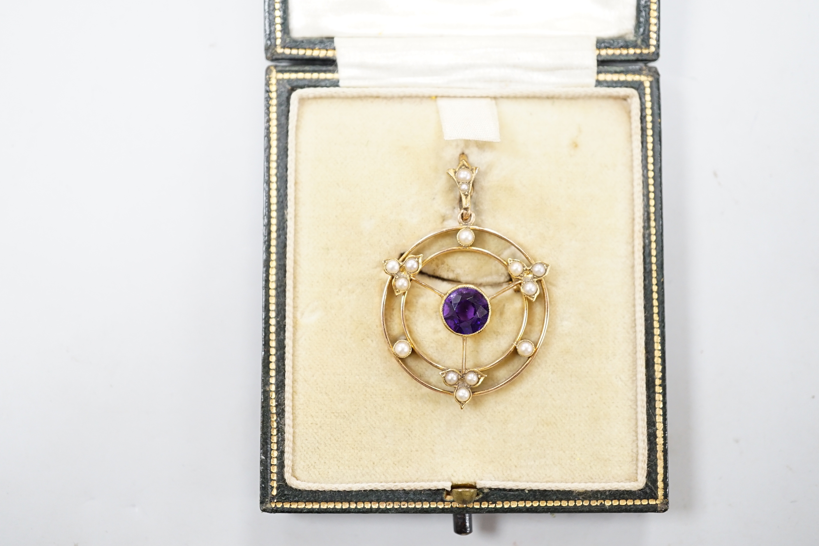 An Edwardian 15ct, amethyst and seed pearl set pendant brooch, overall 36mm, gross weight 4.1 grams, in fitted leather box.